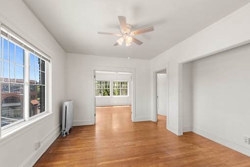 A room with a ceiling fan and a window overlooking a cityscape.
