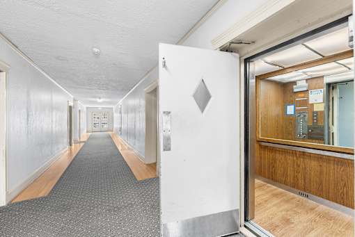 A long hallway with a white door at the end.