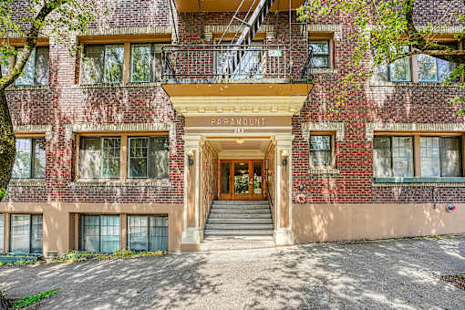 A red brick building with a balcony and a staircase leading to the entrance.