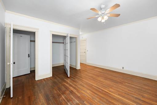 A room with a ceiling fan and wood flooring.