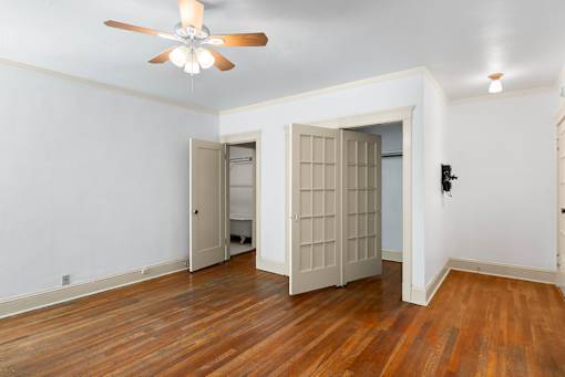 A room with a ceiling fan and wooden floors.