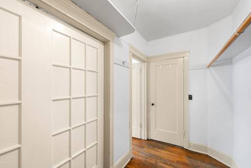 A hallway with a white door and a white wall.