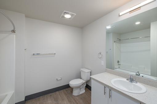A white bathroom with a toilet, sink, and mirror.