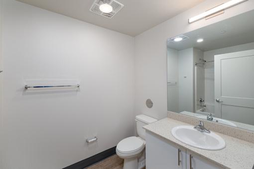 A white bathroom with a toilet, sink, and mirror.
