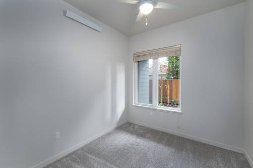A room with a window and a fan on the ceiling.