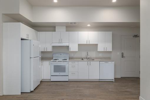 A white kitchen with a refrigerator, oven, and sink.