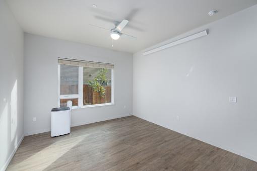 A room with a ceiling fan and a window with a plant on the windowsill.