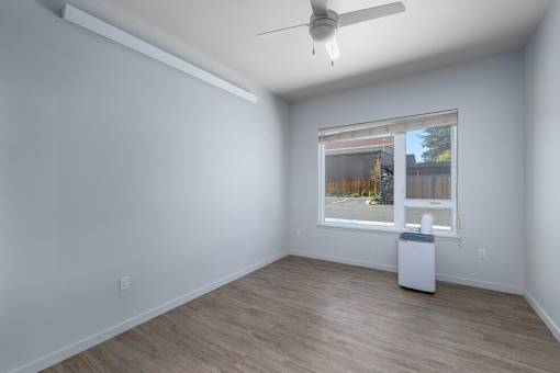 A room with a window and a fan on the ceiling.
