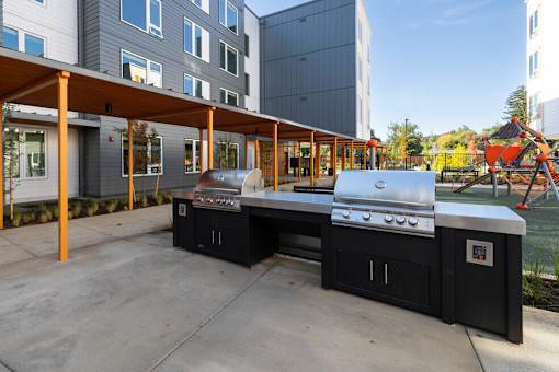A BBQ grill is in the middle of a concrete patio.