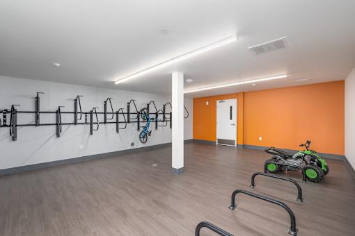 A gym with orange walls and a row of exercise bikes.