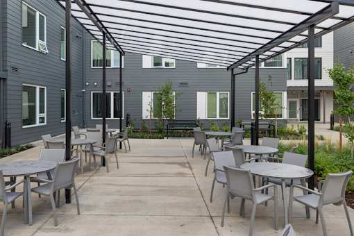 A patio with tables and chairs is surrounded by apartment buildings.