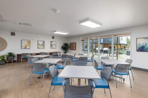 A room with tables and chairs and a painting on the wall.