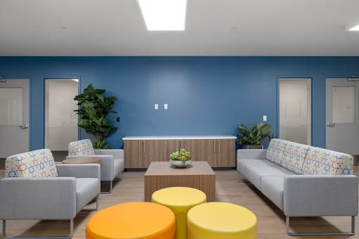 A blue room with grey couches and yellow ottomans.