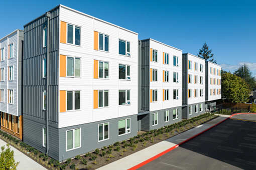 A row of modern buildings with grey, white and orange panels.