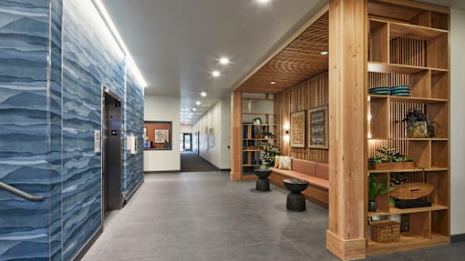 A long hallway with a blue wall on the left and a wooden shelf on the right.