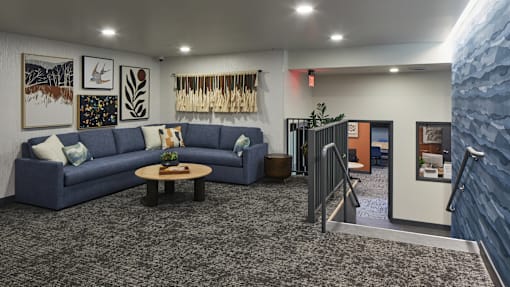 A blue couch is in the middle of a room with a grey carpet.