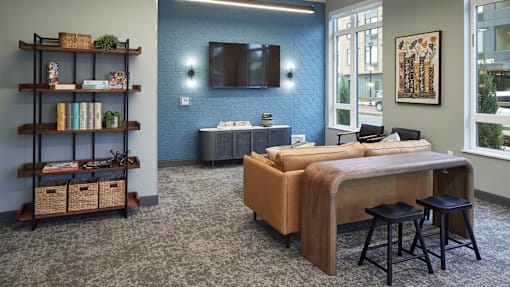 A bedroom with a bed, a shelf with baskets and books, and a window with a view of the city.