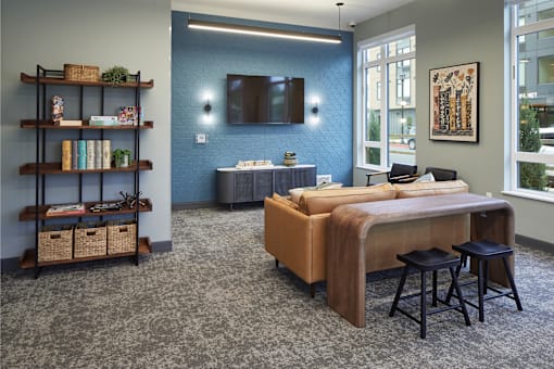A bedroom with a bed, a shelf with baskets and books, a chair, and a painting on the wall.