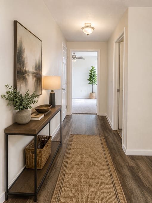 A hallway with a brown carpet and a painting on the wall.