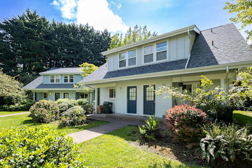A white house with a grey roof and a green door.