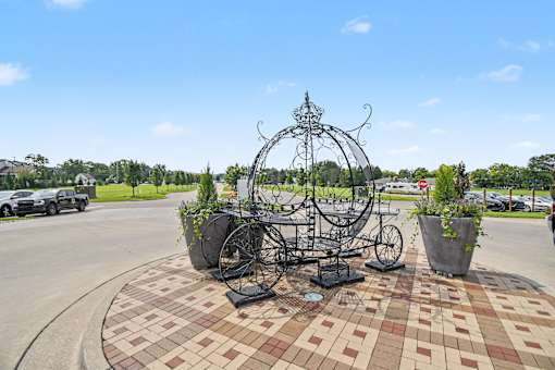 A large metal bicycle sculpture is in the middle of a brick courtyard.