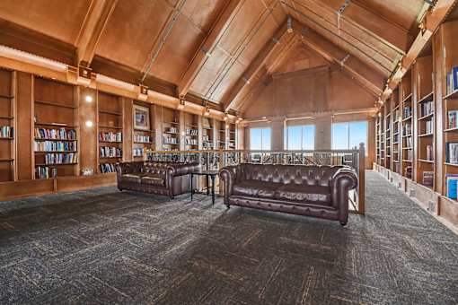 A library with brown leather couches and bookshelves.