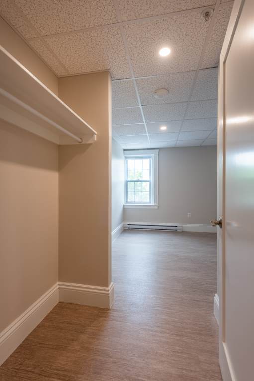 A long, narrow hallway with a window and a door at the end.