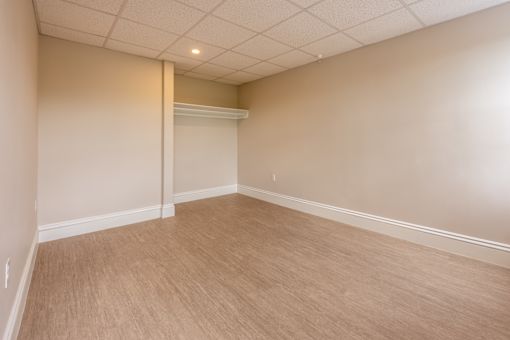 Empty room with a white ceiling and light wood floor.