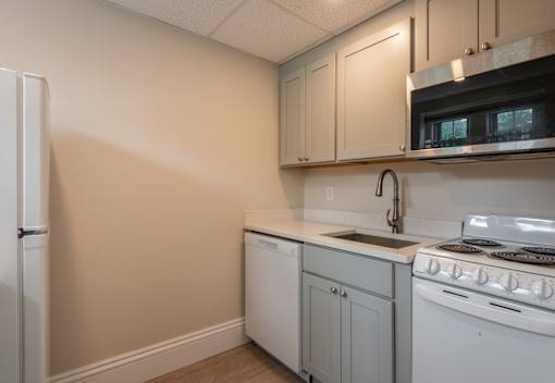 A kitchen with white appliances and cabinets.
