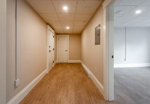 A long, narrow hallway with wood flooring and white walls.