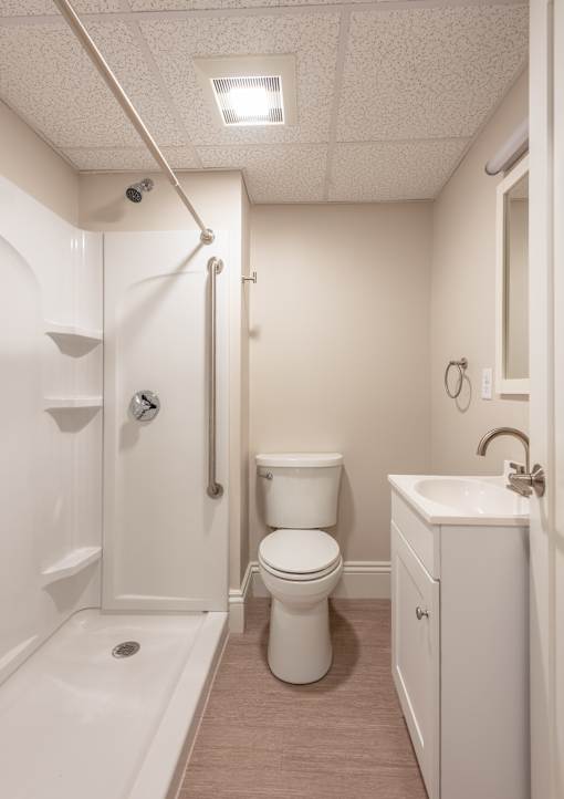 A white bathroom with a toilet, sink, and shower.