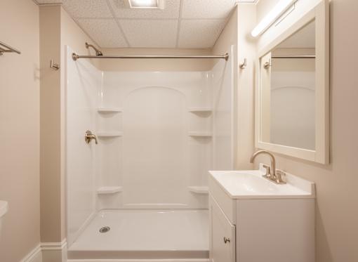 A white bathroom with a sink, mirror, and bathtub.