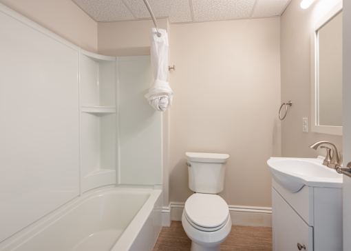 A white bathroom with a toilet, sink, and bathtub.