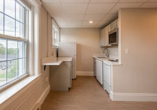 A kitchen with white appliances and a window.