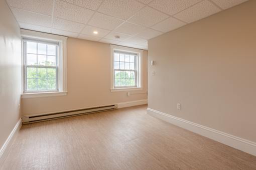 A room with two windows and a radiator on the wall.