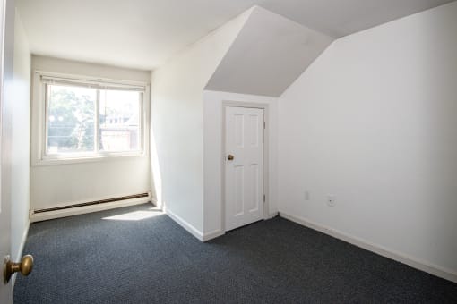 an empty bedroom with a door and a window