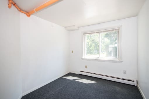 a small room with white walls and a large window