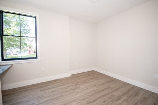 an empty room with a large window and wooden floors