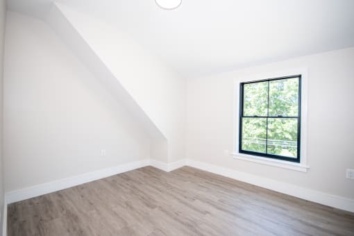 an empty bedroom with white walls and a large window