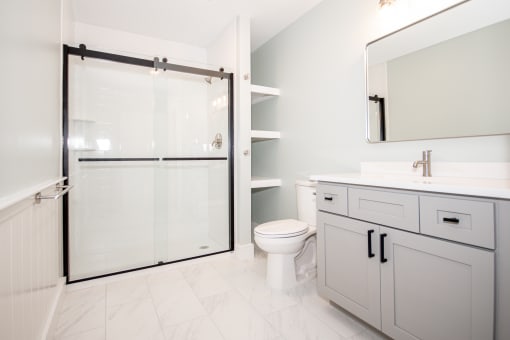a large bathroom with a white sink and toilet next to a shower with a sliding glass door
