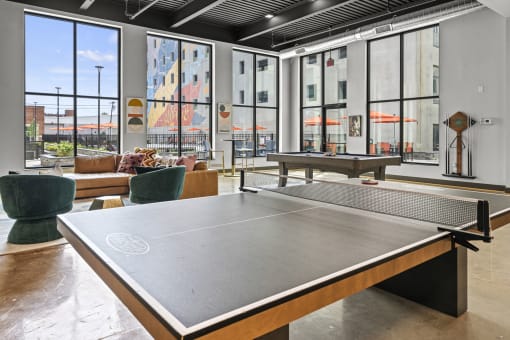 a ping pong table sits in the middle of a room with large windows  at The Icon, Richmond, VA, 23230
