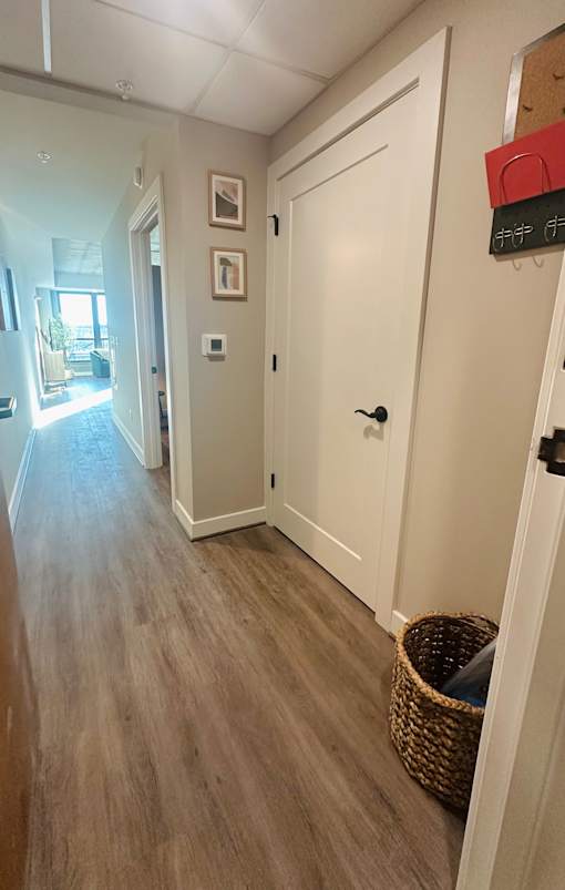 A hallway with a white door and a basket on the floor.
