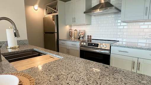 A kitchen with granite countertops and white cabinets.