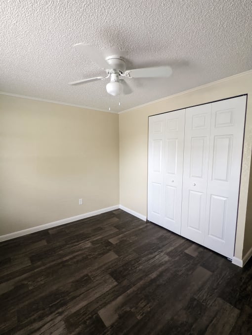 an empty bedroom with a ceiling fan and a closet