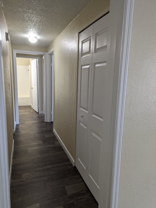 a hallway with white doors and a wood flooring in a home