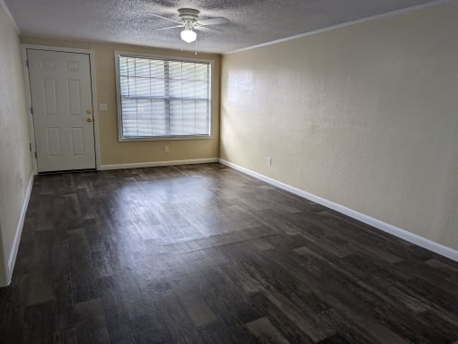 an empty living room with wood floors and a window