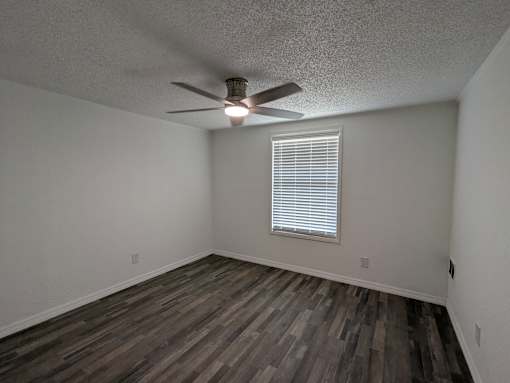 A room with a ceiling fan and a window with blinds.