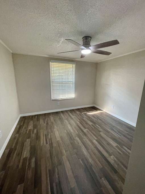 A room with a ceiling fan and wooden flooring.