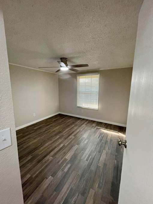 A room with a ceiling fan and wooden flooring.