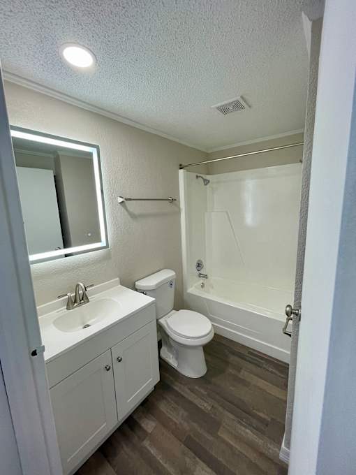 A white bathroom with a toilet, sink, and shower.